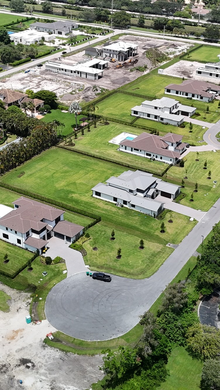 Drone view of a new-construction community with tile and metal roofs