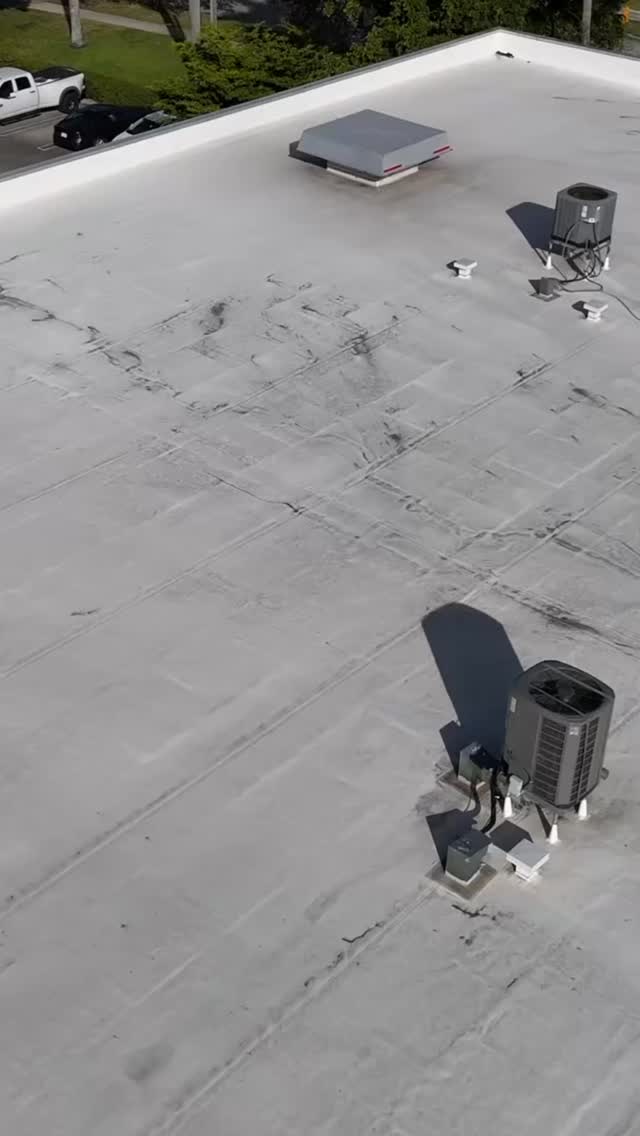 Drone view of a stained commercial flat roof with AC units
