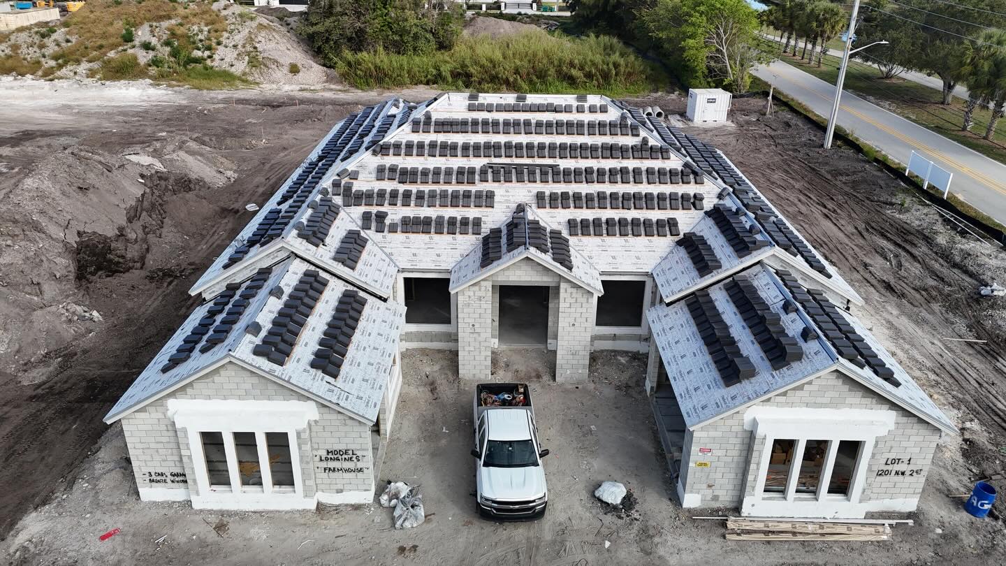 Drone view of a new-construction home with roof tile loaded on new underlayment